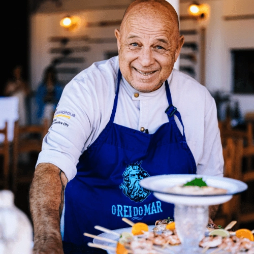 Imagem 1 A gastronomia do Réveillon Campeche terá a assinatura de Narbal Corrêa — O Rei do Mar, chef, pesquisador, pescador submarino, empresário e autor que construiu sua trajetória a partir de uma relação profunda com o oceano e com a gastronomia de frutos do mar. Natural de Florianópolis, Narbal reúne décadas de experiência entre restaurantes, consultorias e mais de mil eventos gastronômicos realizados no Brasil e no exterior. Sua cozinha combina técnica, conhecimento da origem dos ingredientes e respeito à matéria-prima, em uma trajetória que passou por projetos reconhecidos da gastronomia catarinense e por experiências no Caribe, Mediterrâneo e diferentes regiões do Brasil.
No Réveillon Campeche, Narbal será o responsável pela criação e condução de toda a experiência gastronômica do evento, assinando o Open Food servido ao longo da noite. A proposta é levar para a virada uma gastronomia conectada ao território, ao mar e ao jeito de viver o Campeche, transformando a comida em um dos grandes protagonistas da experiência. Mais do que um serviço de alimentação, será uma mesa pensada para celebrar: boa comida, ingredientes selecionados e a assinatura de um chef que fez do mar a inspiração de uma vida inteira.